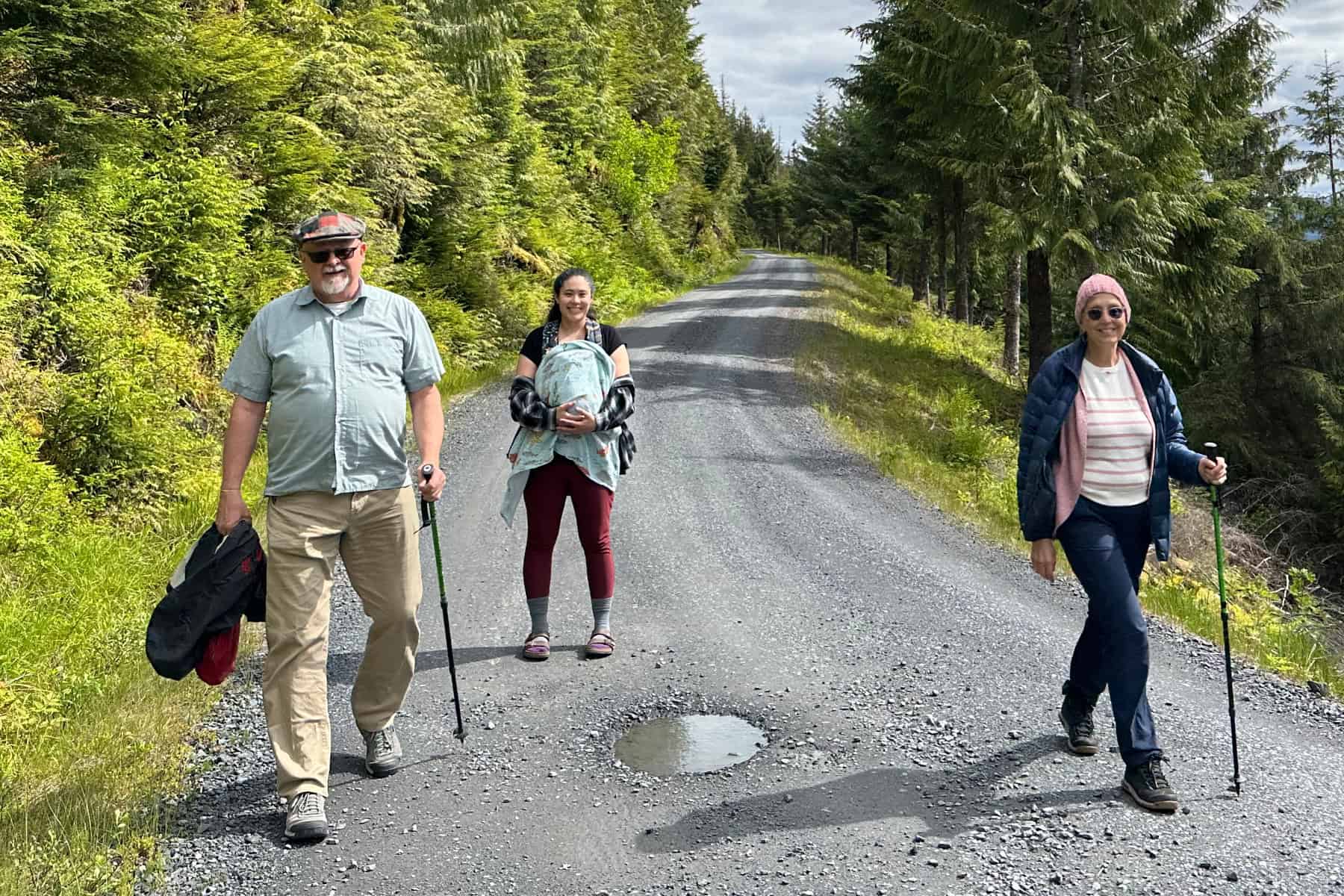 Visitors walking on a forested gravel road in Southeast Alaska