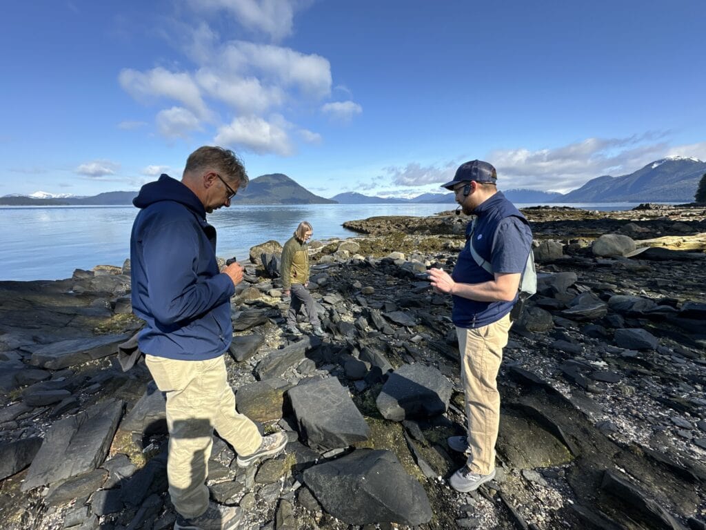 Tourists exploring Petroglyph Historic Beach shoreline during guided walk in Wrangell, Alaska.